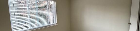 A small window with bars on the side is in a room with a grey wall.